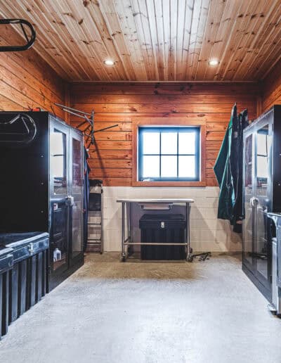 tack room with black accessories and storage and warm wood walls