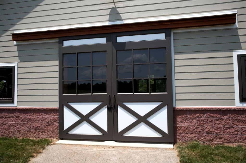 Stylish black and white barn garage doors with window accents, ideal for residential properties.