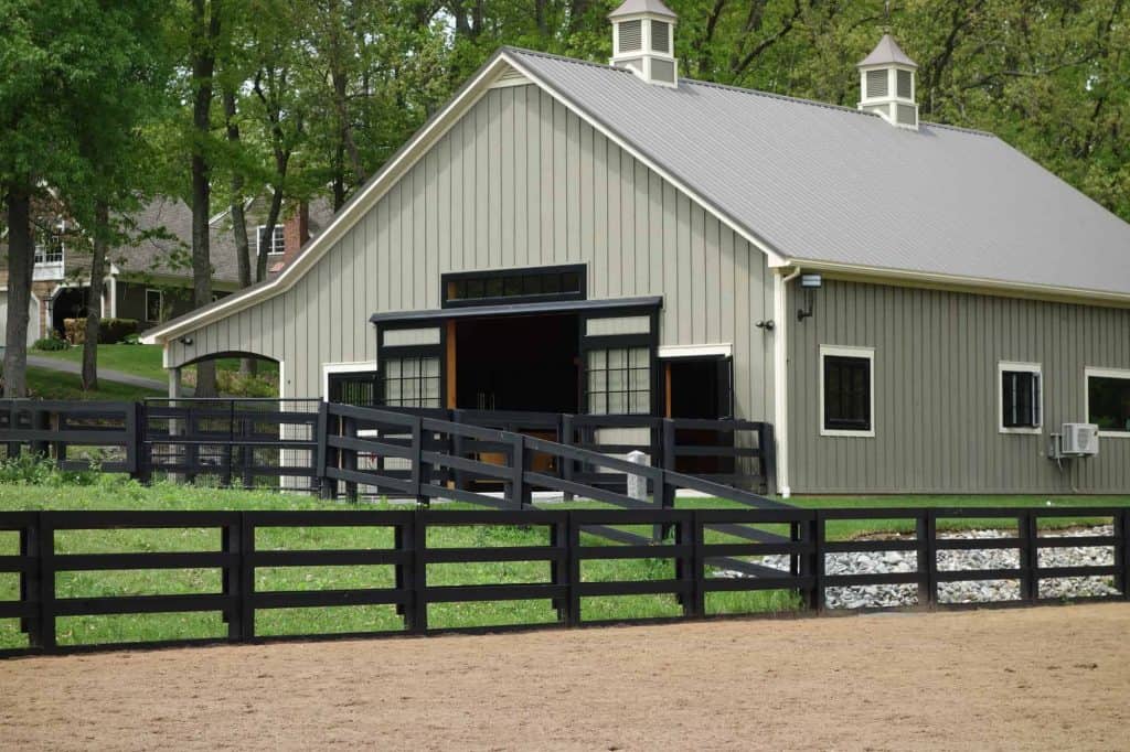 Elegant new barn with black fencing and large windows, perfect for equestrian and event needs.