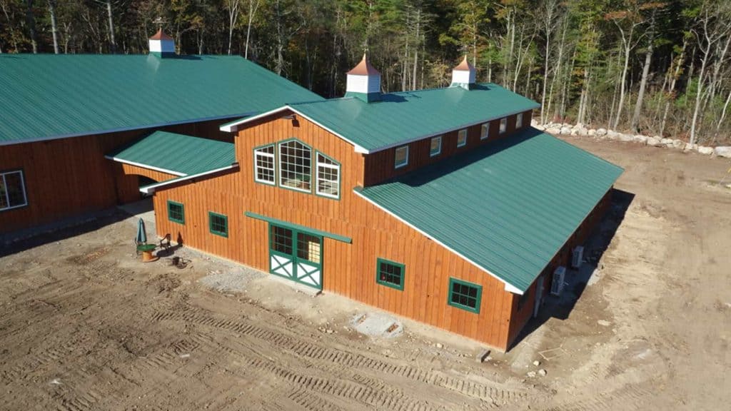 Aerial view of a custom barn with green metal roof and weathered wood siding built by Quarry View Building Group.