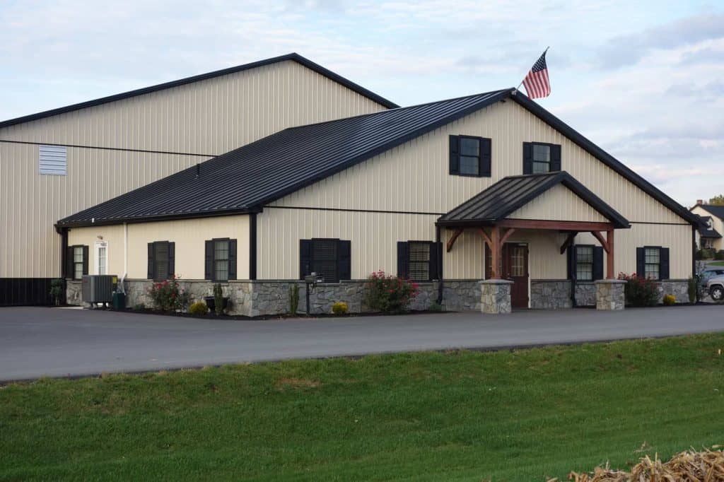 Commercial building with stone base, black metal roof, and American flag.