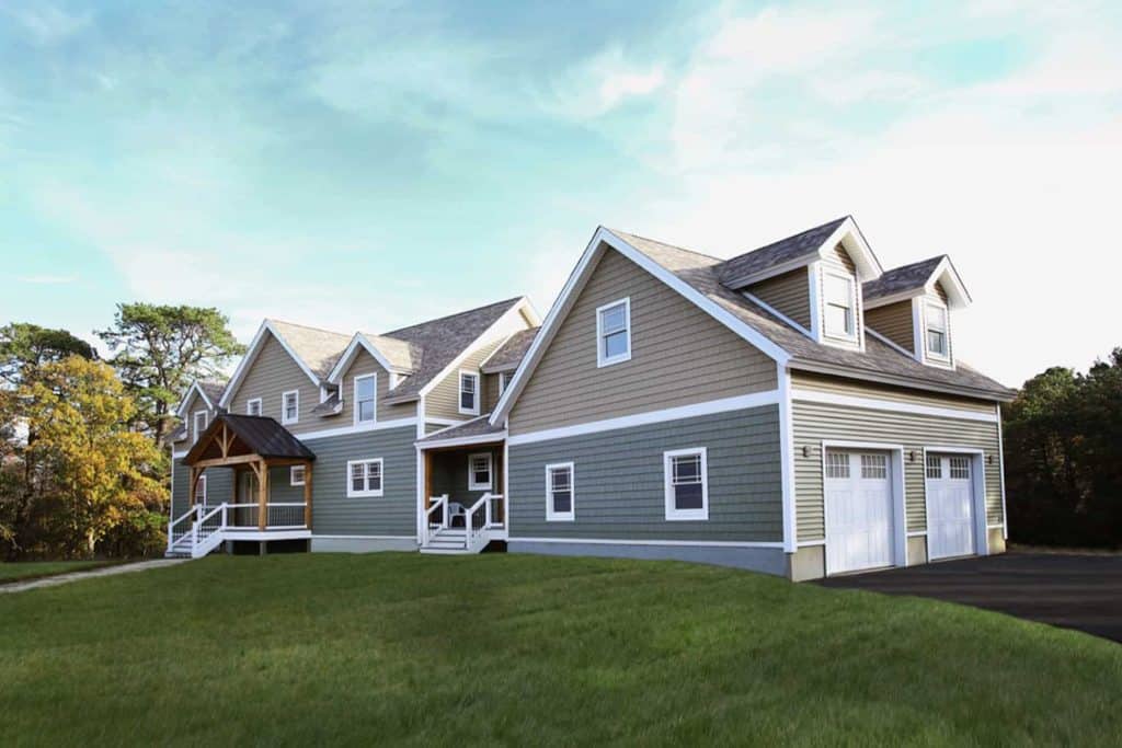 Beautiful new house with gray siding, white trim, and a two-car garage, set in a landscaped yard.