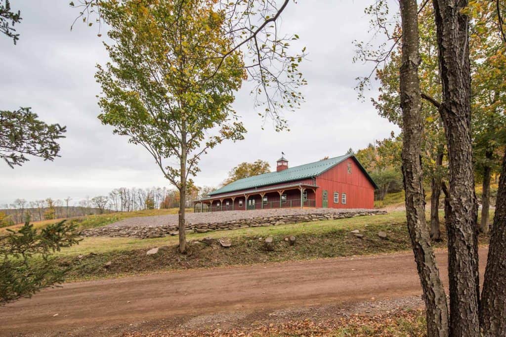 Charming red barn with green roof surrounded by autumn trees, scenic quarry view, perfect for rustic events.