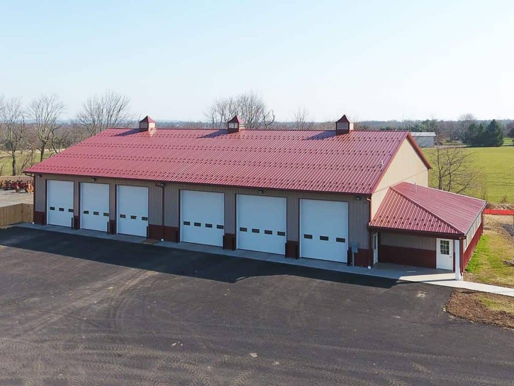 A modern storage facility with a red metal roof and large garage doors, designed for efficient storage solutions.