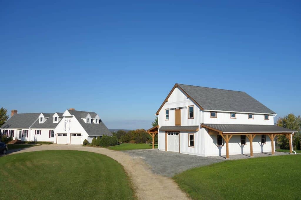 Beautiful farmhouse-style building with white exterior, wooden trim, and a spacious driveway.