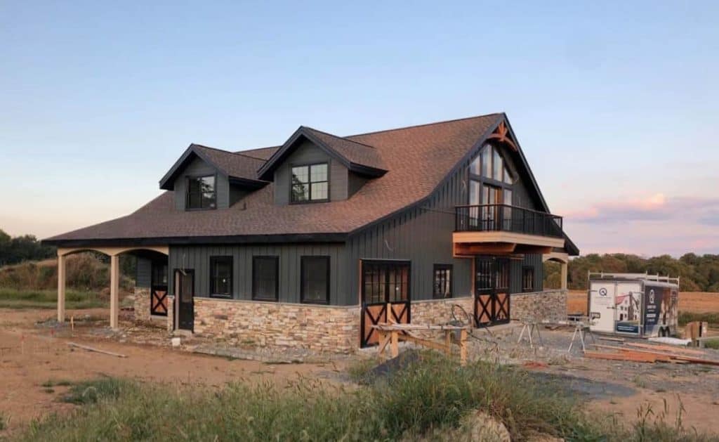 Beautiful custom-built rural house with stone foundation, black exterior, and balcony design.