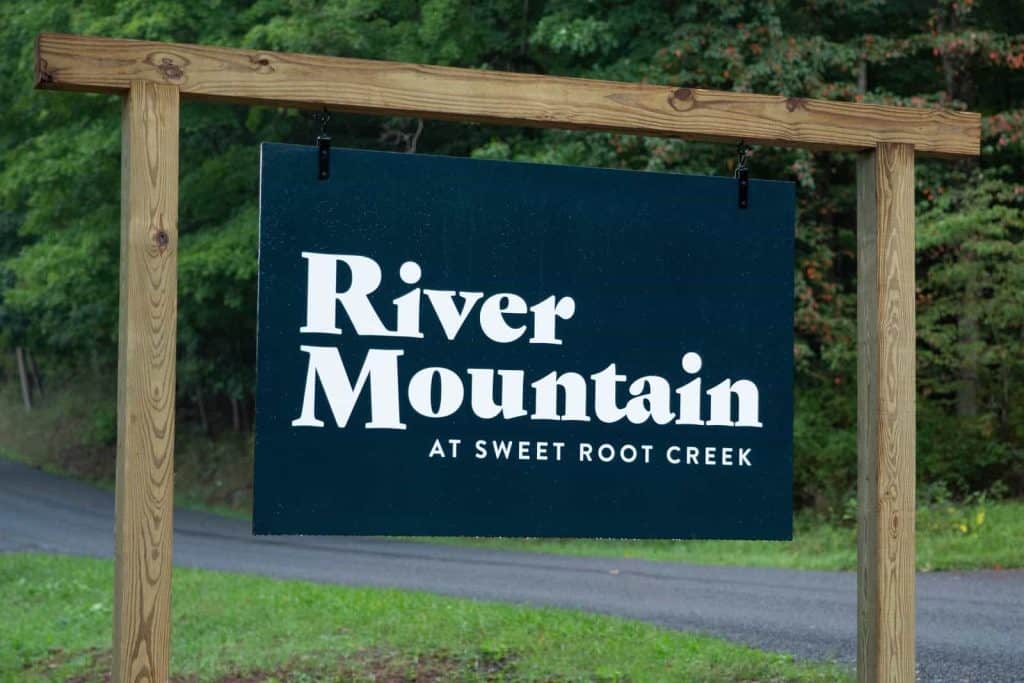 Modern outdoor sign promoting River Mountain community at Sweet Root Creek.