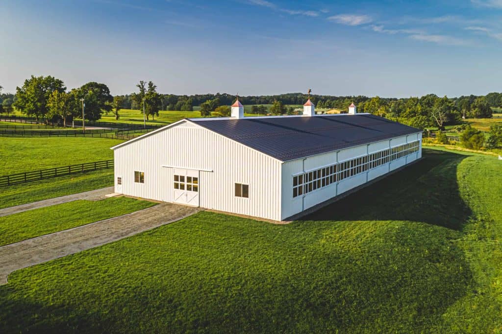 Spacious white barn with large windows and historic rooftops, perfect for events or agricultural use.