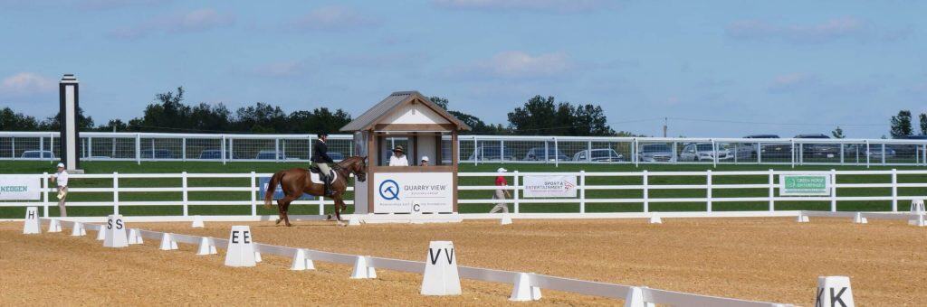Horse riding event with riders and spectators in the outdoor arena.