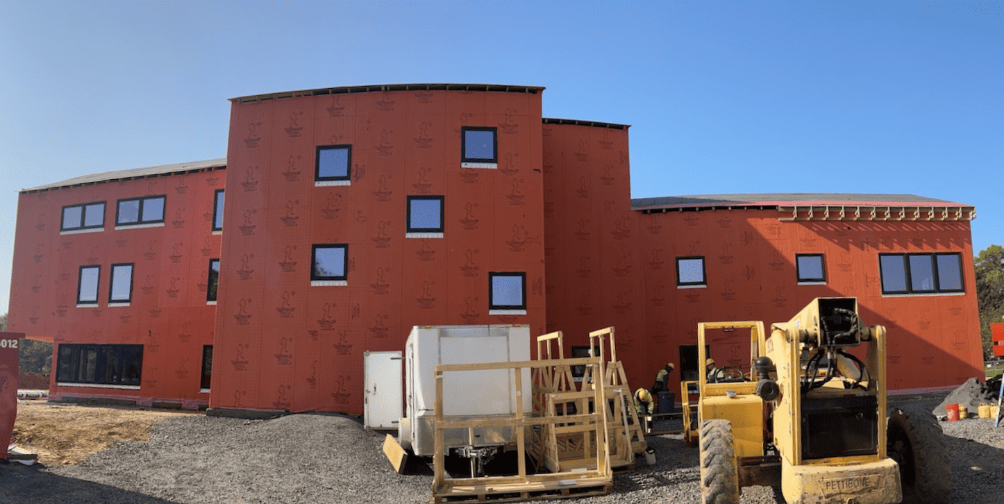 Passive house dormitory under construction with orange wrap