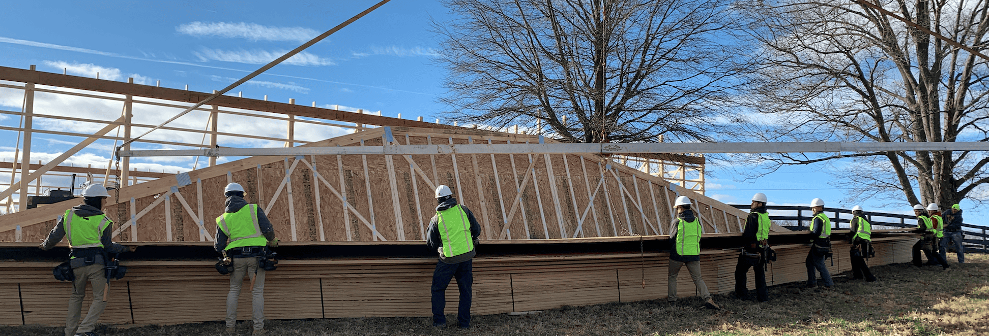 construction team moving truss off of pile in their safety gear