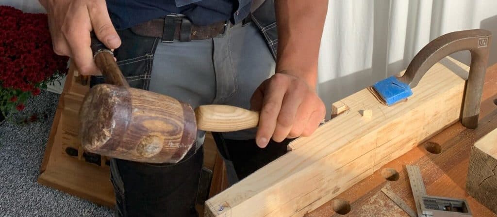 Close-up of a craftsman hammering wood during custom furniture building process at Quarry View Building Group.