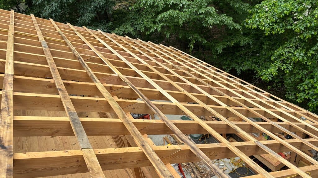 Construction of roof framing with wooden beams and rafters for a residential building.