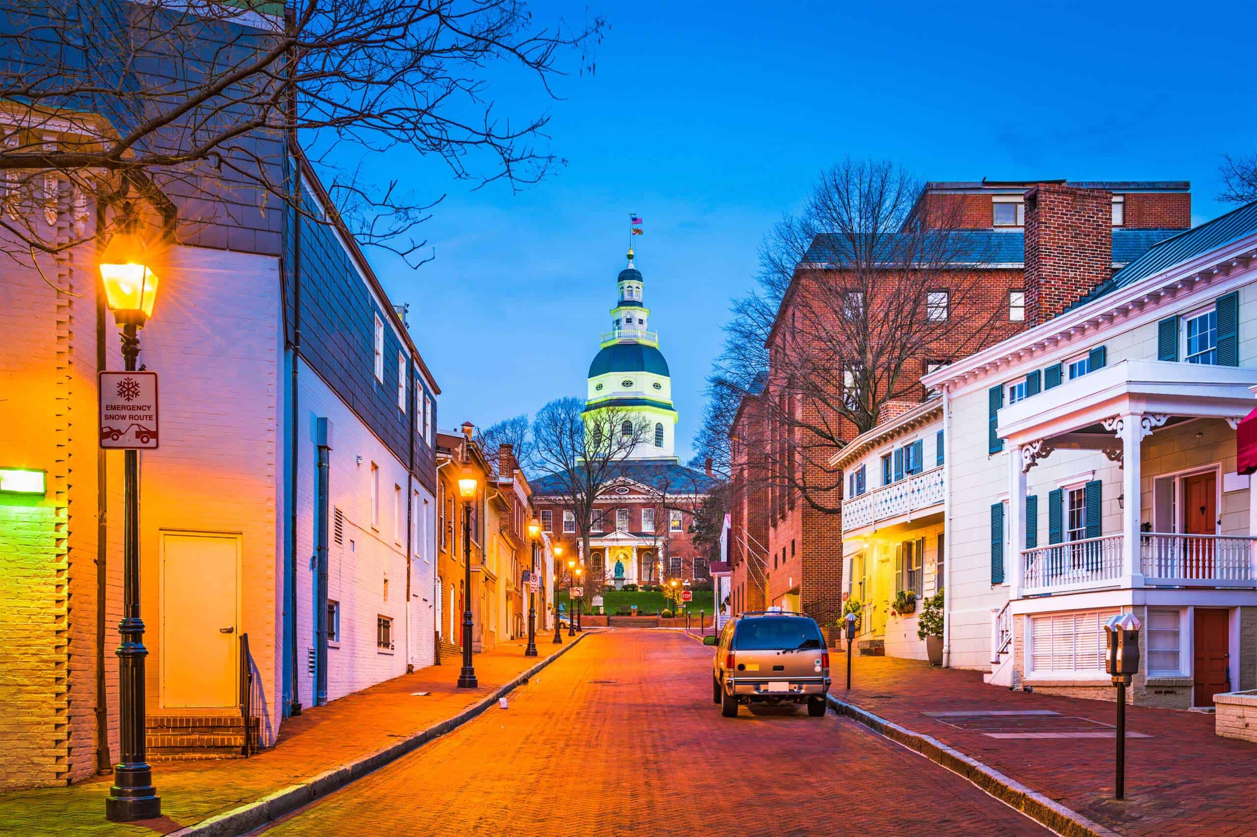 Colorful street scene of historic buildings with church steeple in the background.