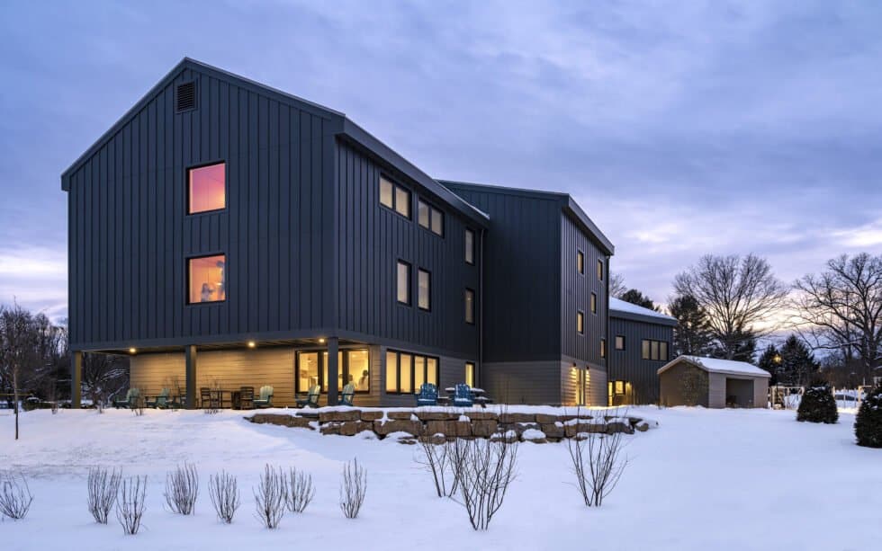 Stylish black metal siding with large windows in a snowy landscape.
