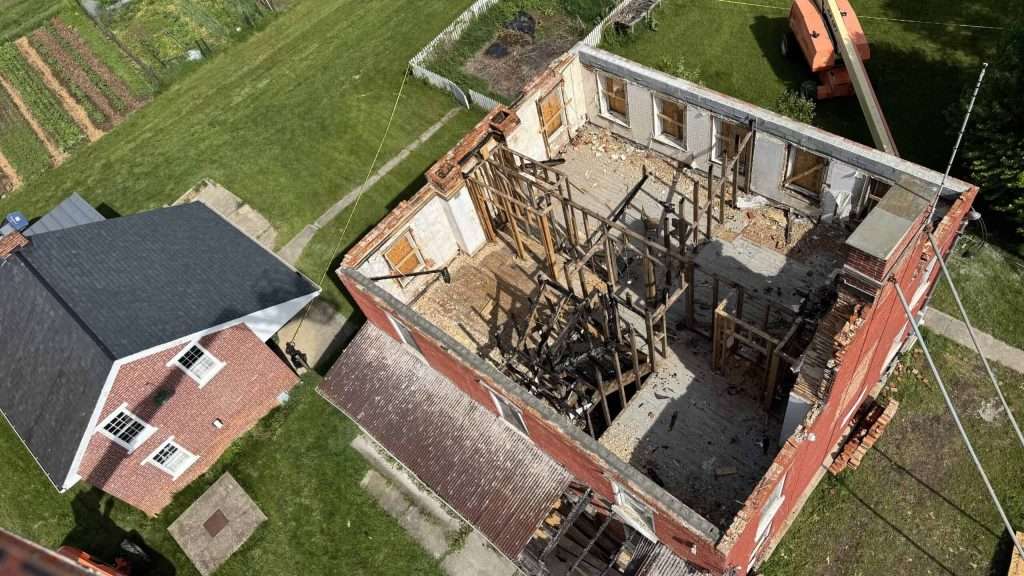 Aerial view of a house renovation project showing exposed walls and construction scaffolding, highlighting professional building restoration.