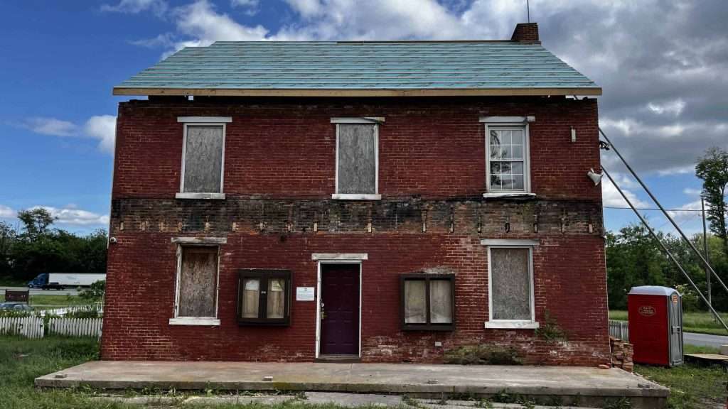 Historic brick building undergoing restoration with boarded-up windows in progress.