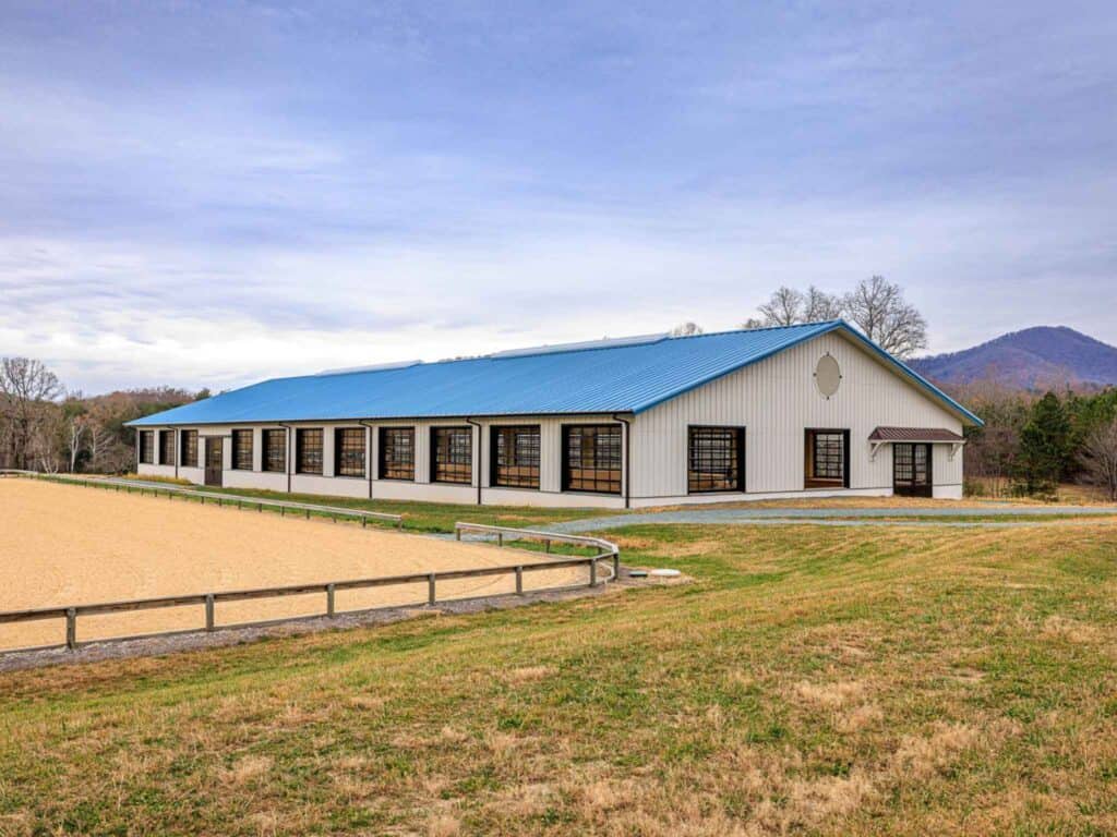Exterior of a 100′ x 240′ steel indoor riding arena with a blue roof in Virginia, built for an Olympic equestrian.