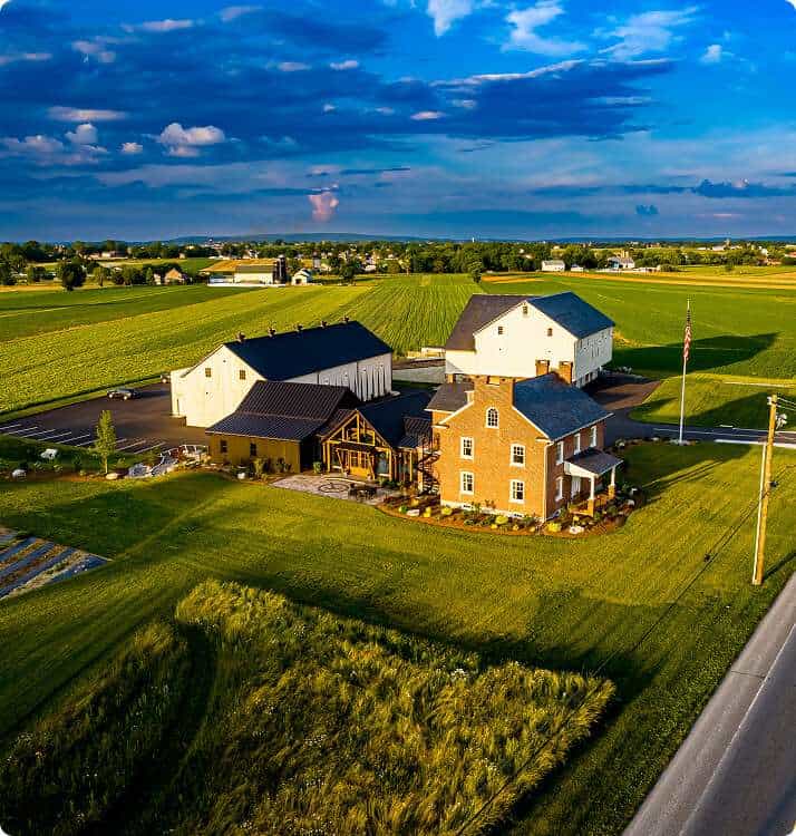 Scenic rural construction site with barn-style buildings and open fields.