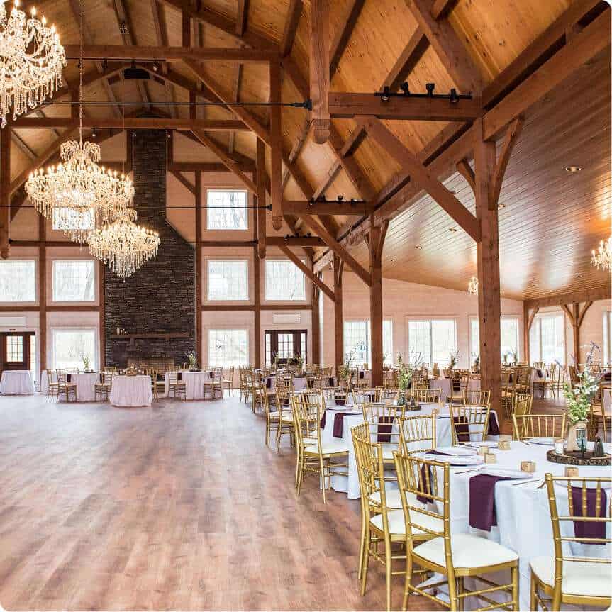 Elegant barn wedding venue with wooden beams, chandeliers, and large windows. Perfect for weddings and events.