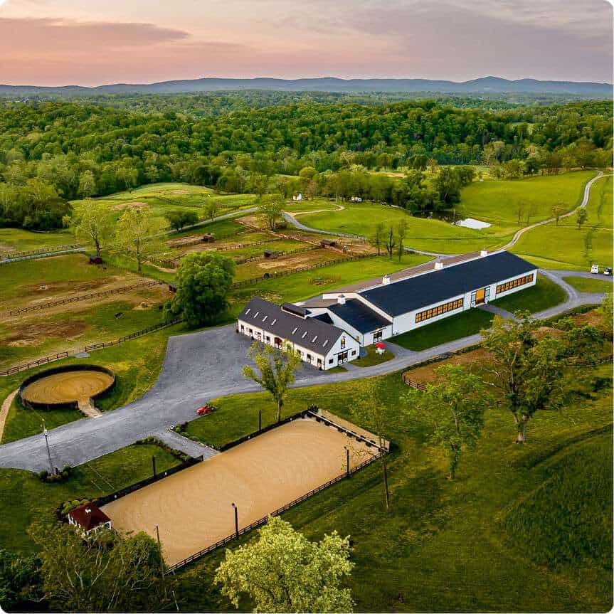Aerial view of the Quarry View Building Group horse stable, surrounded by lush green landscape and riding arenas.