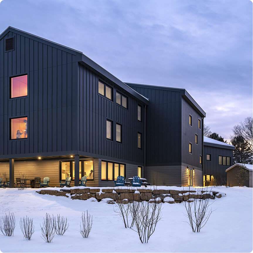 Blue modern siding commercial building with large windows, outdoor seating, and snow-covered landscape.