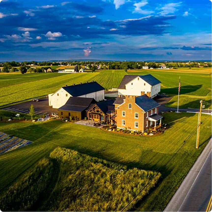 Beautiful rural farmstead with modern and historic buildings in lush green landscape.