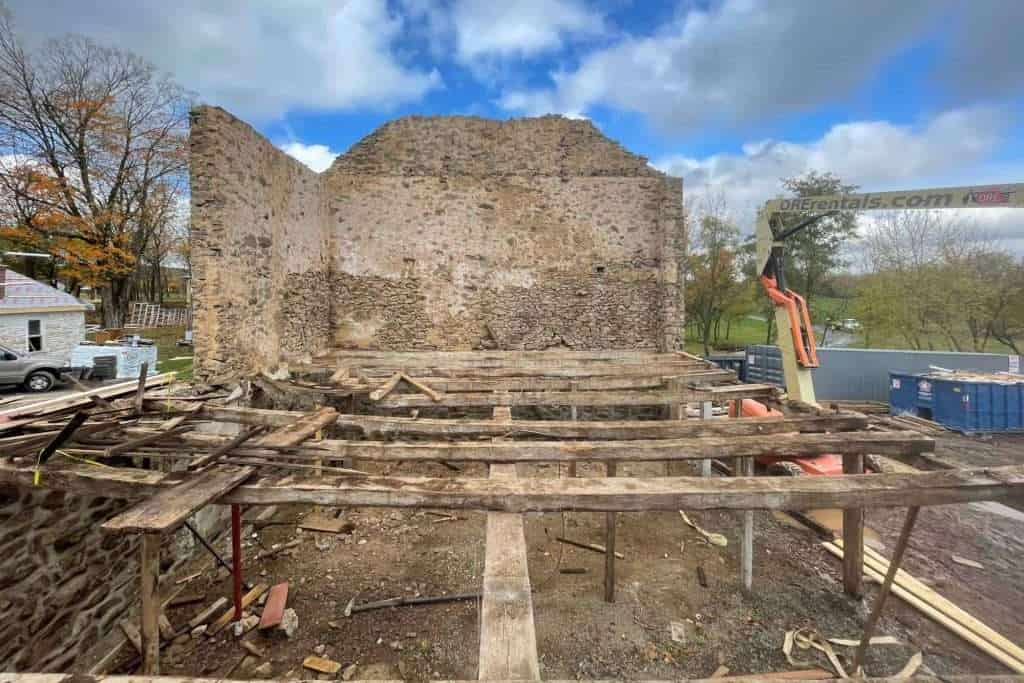 Extensive construction on an old stone building with scaffolding and machinery.