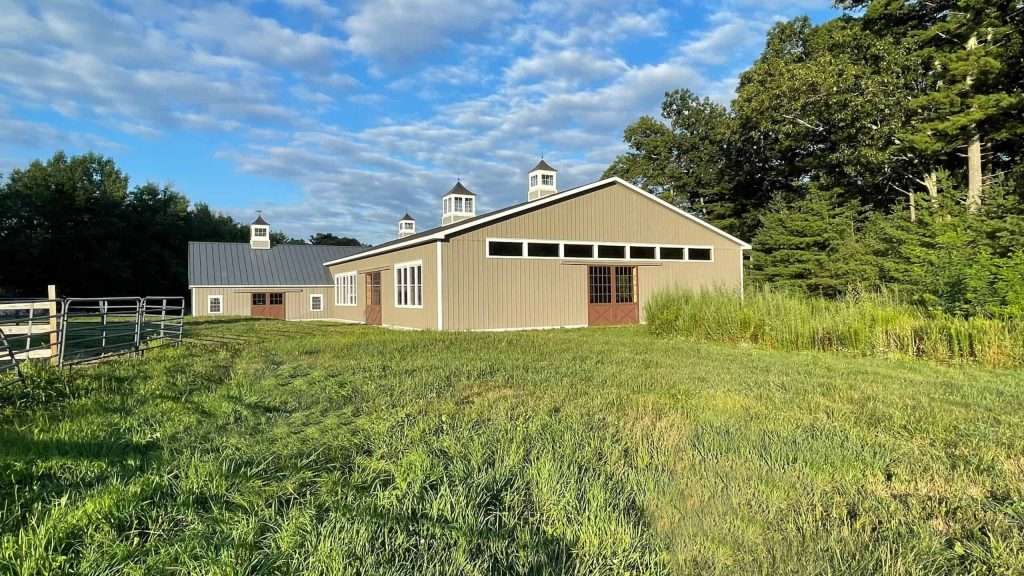 Beautiful rural barn built by Quarry View Building Group amidst vibrant greenery and blue sky.