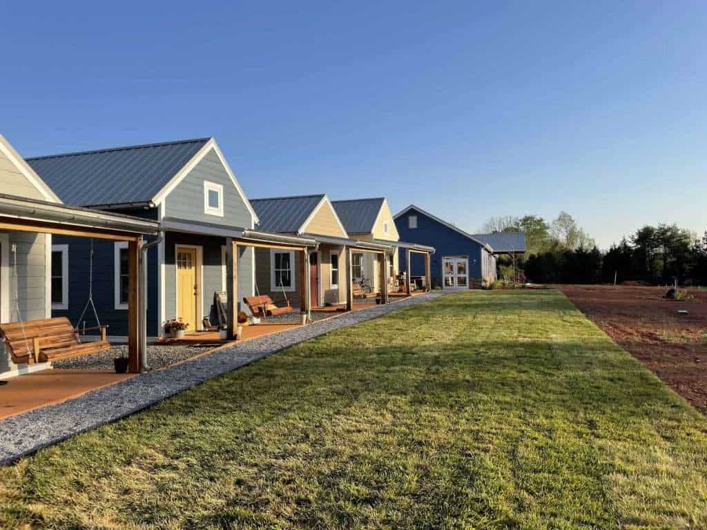 Modern custom homes with vibrant exterior paint, outdoor seating areas, and well-maintained lawns.