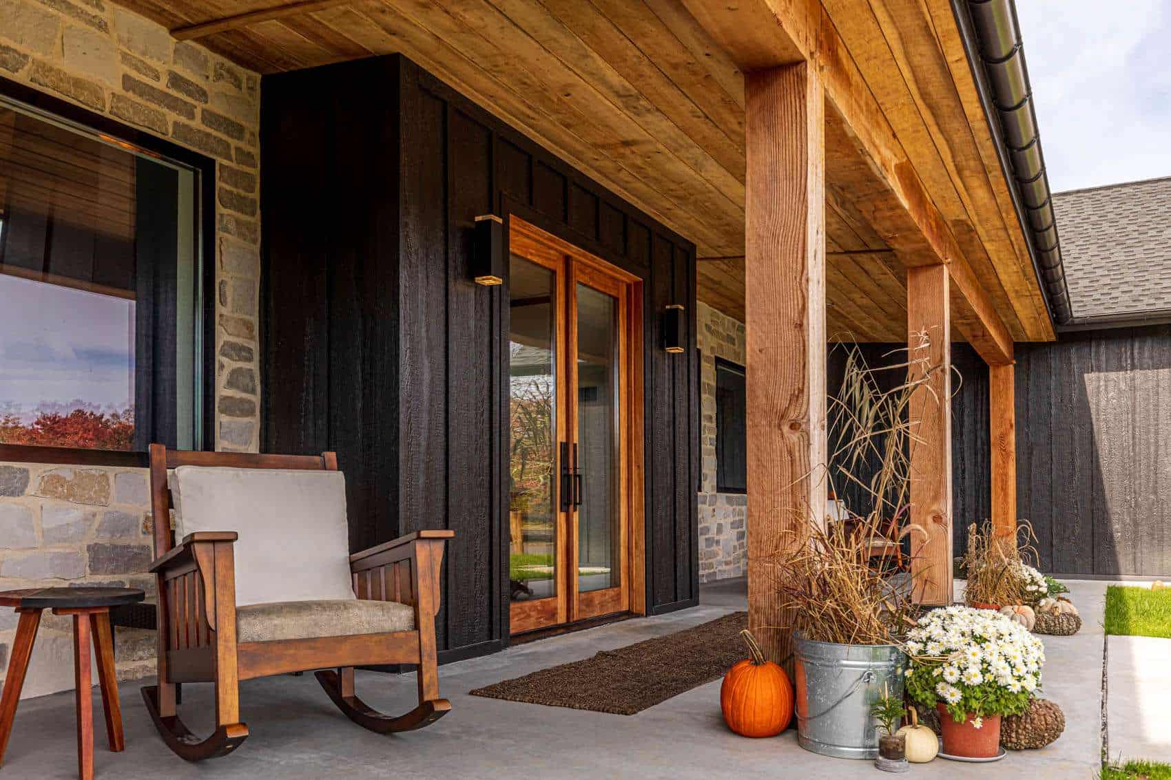 Versatile house exterior featuring a rustic porch, black siding, and natural stone accents, designed by Quarry View Building Group.