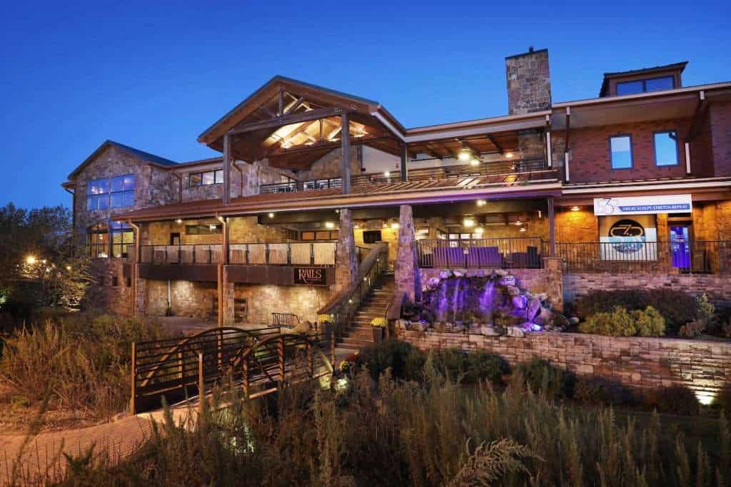 Elegant building with stone facade, multiple outdoor terraces, sunset lighting, and lush landscaping.