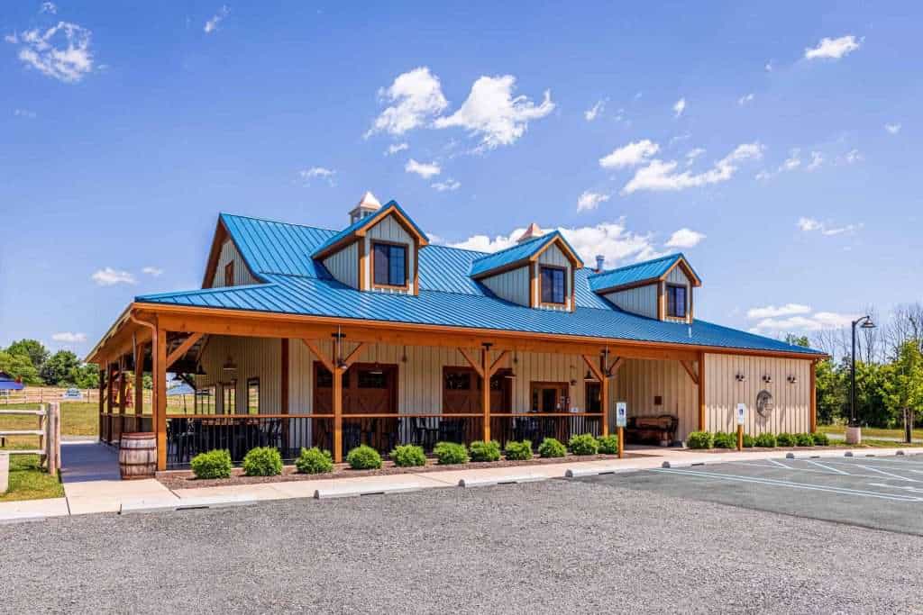 A charming rustic building with a vibrant blue metal roof and cozy porch, designed for modern functionality and aesthetic appeal.