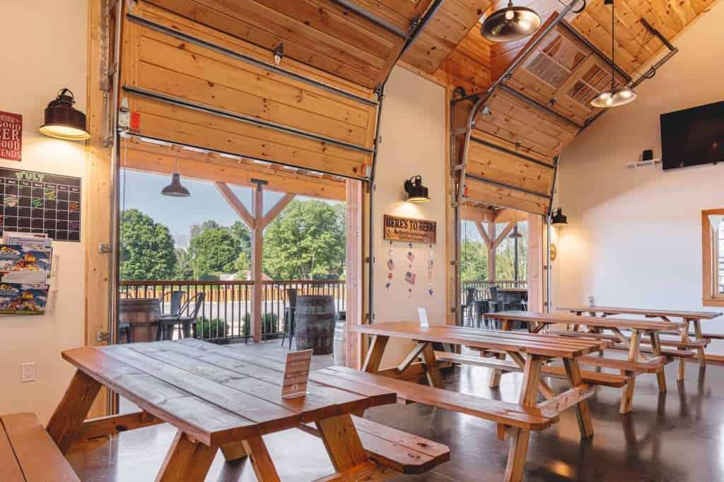 Inviting brewery interior with rustic wood decor and open garage-style doors, perfect for outdoor gatherings.