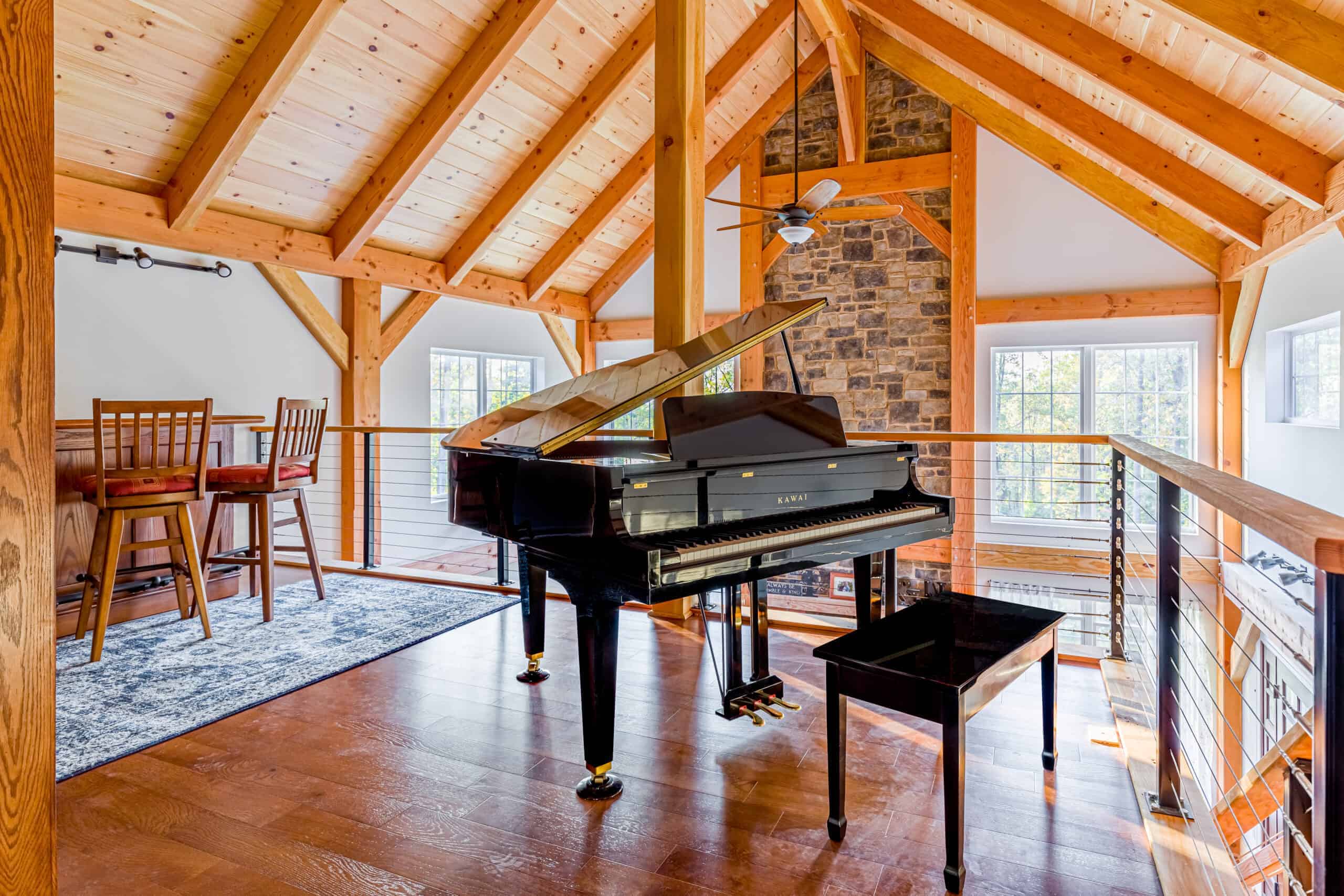 Bright, spacious home interior showcasing a black grand piano on a wooden floor by large windows and exposed wooden beams.