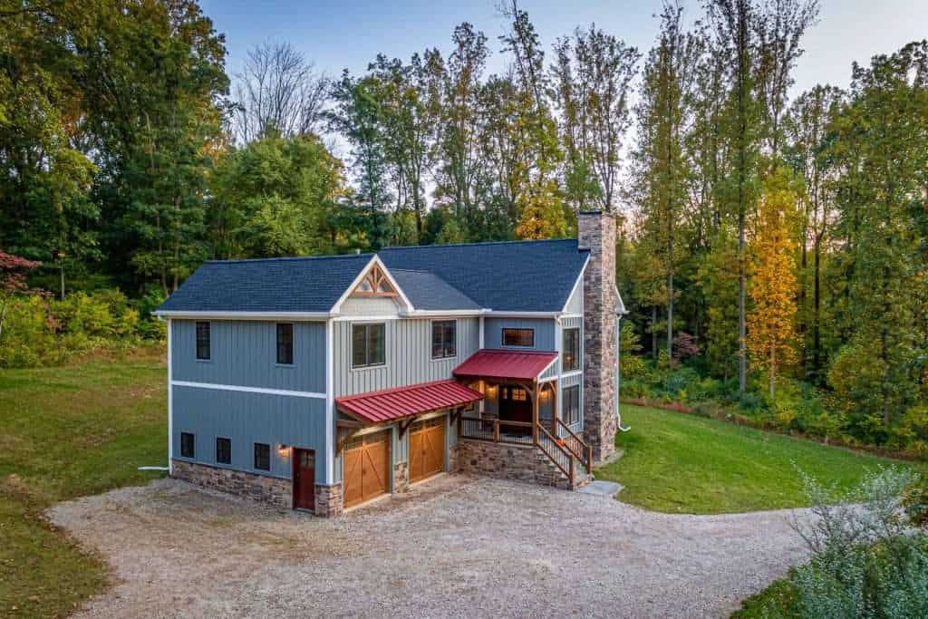Vintage barn door garage, cozy porch, surrounded by lush trees, scenic countryside setting.