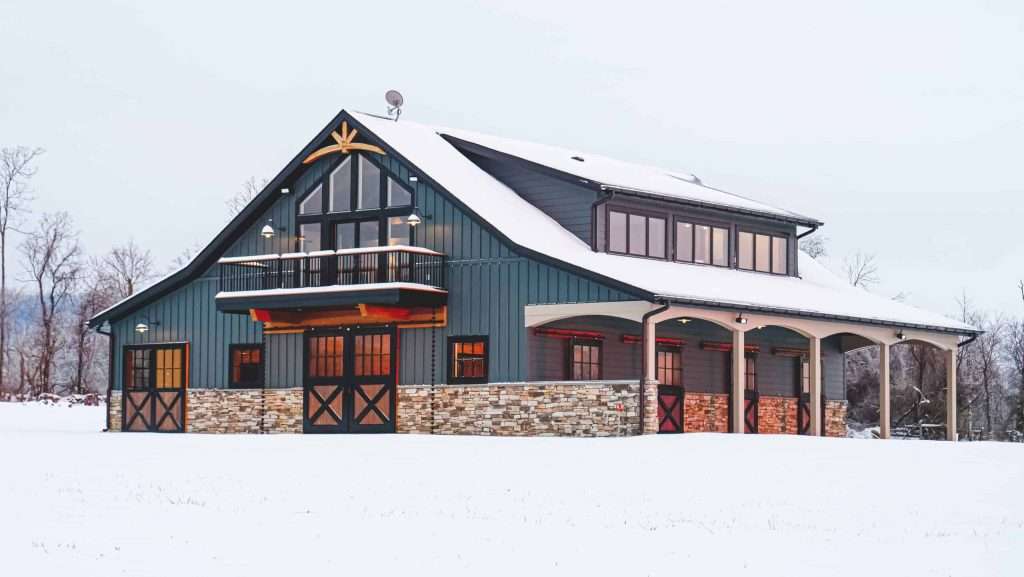 Stylish mountain house featuring a stone exterior, large windows, and spacious outdoor deck in snowy landscape.