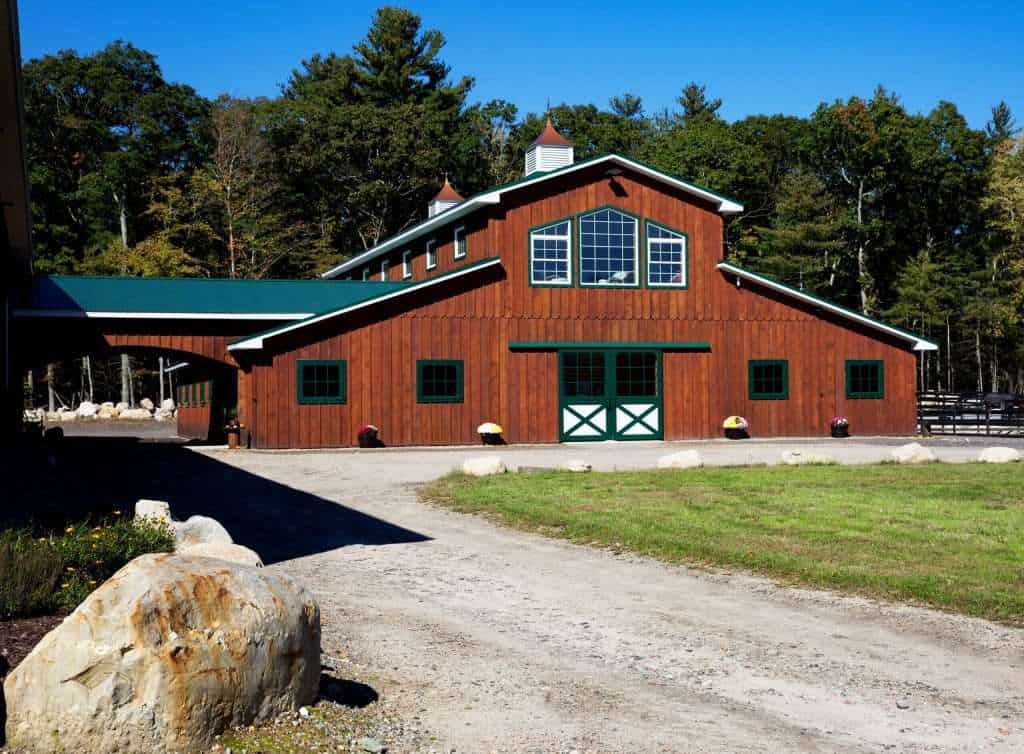 Elegant rustic barn building with wooden exterior, green accents, and surrounding landscape.