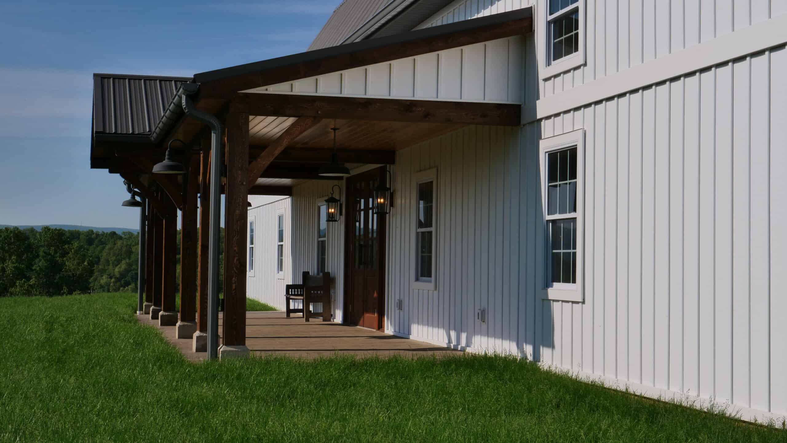 Farmhouse exterior with white siding, wooden porch, and outdoor lighting.