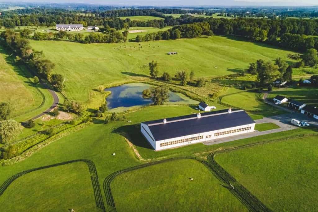 Aerial view of Quarry View Building Group, showcasing a sleek barn-style building amidst scenic green landscape and riding trails.