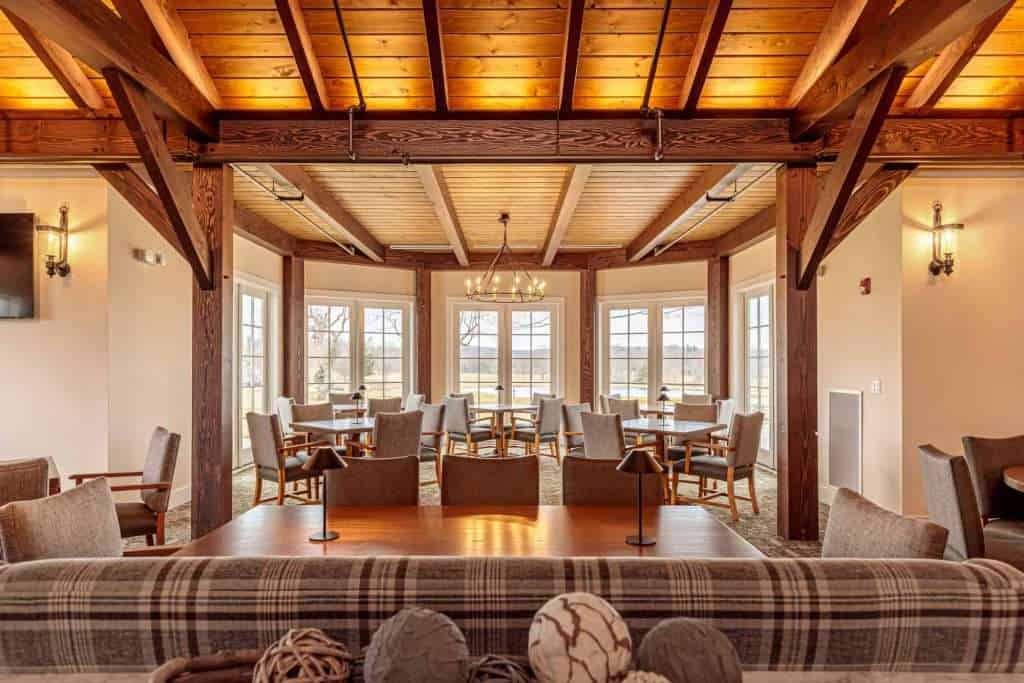 Beautiful rustic building interior featuring wood beams, large windows, and warm lighting for event spaces or hospitality.