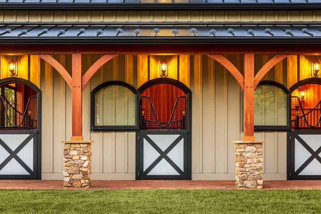 Stunning barn-style structure with wooden beams, stone pillars, and lighting, emphasizing high-quality building craftsmanship.
