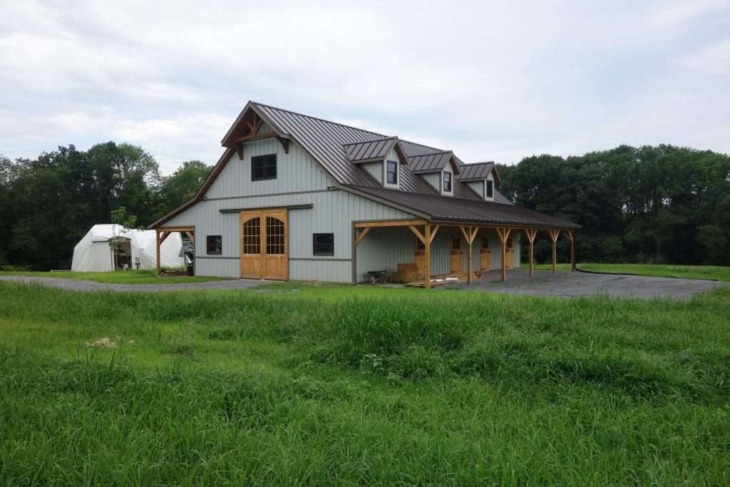 Modern Timber Barn Construction with Green Fields.