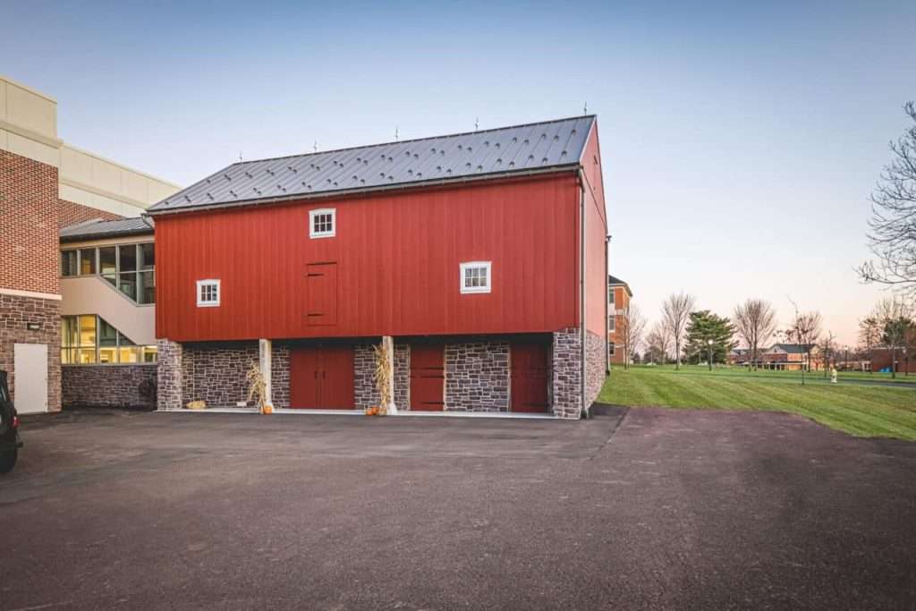 Traditional red barn with stone foundation, scenic park setting, timber accents, rustic charm.