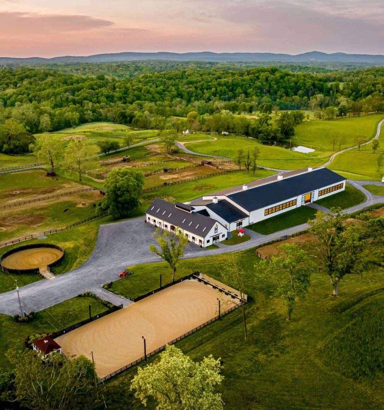 Aerial view of scenic countryside estate with equestrian facilities and lush greenery, showcasing Quarry View Building Group services.