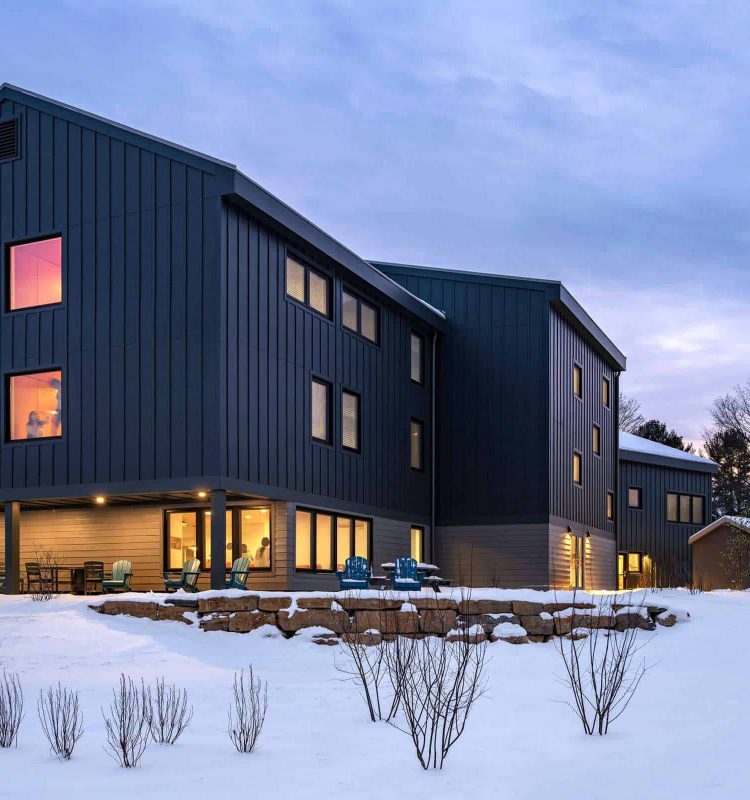 Elegant contemporary black house with large windows and a snowy yard, showcasing quality construction by Quarry View Building Group.
